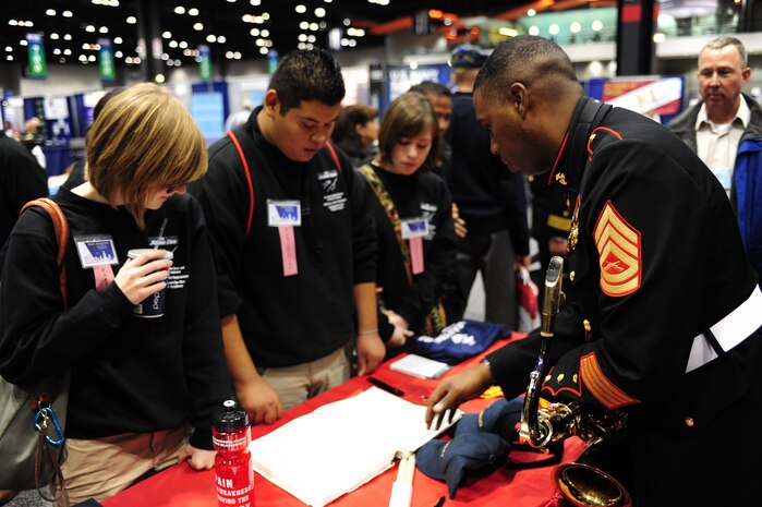 Gunnery Sgt. Jason Knuckles, the musician technical assistant for the 9th Marine Corps District, speaks to a group of high school students at a Marine Corps Music Program booth, during the 2011 Midwest Clinic, Dec. 14. The Midwest Clinic is an annual event to promote music education.